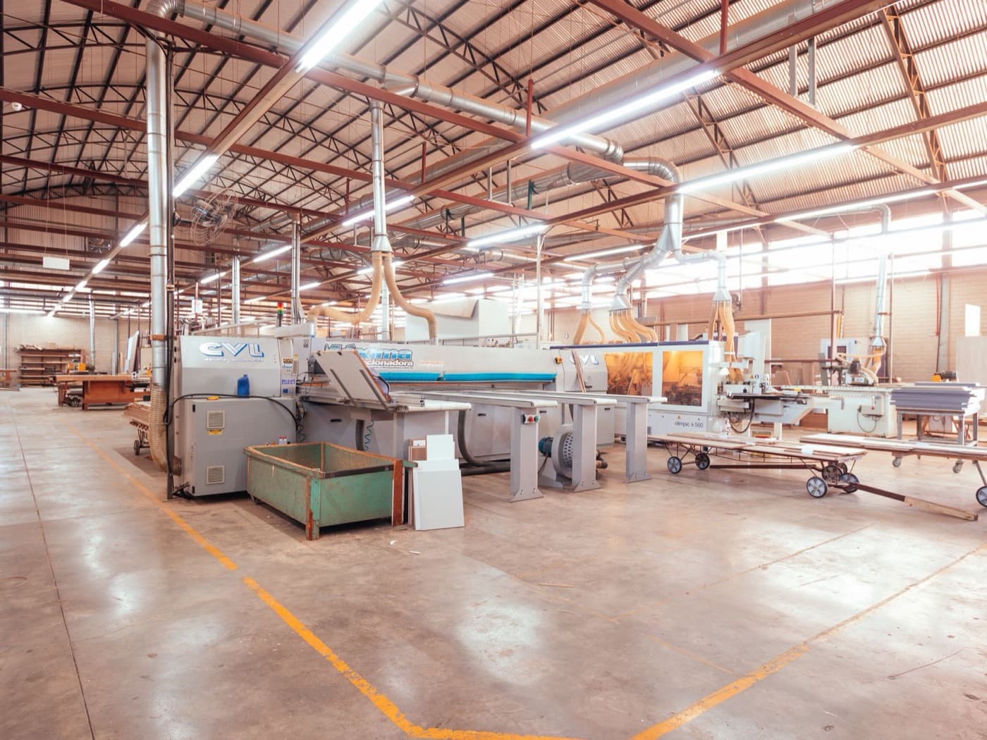 A clean, well-lit wood shop with panel saws and racks of finished panels